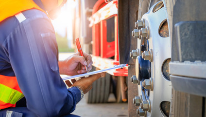 Preforming a pre-trip inspection on a truck,Concept preventive maintenance truck checklist,Truck driver holding clipboard with checking of truck,spot focus. © KM.Photo