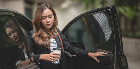 Obraz na płótnie Canvas Beautiful businesswoman getting out of the modern luxury car