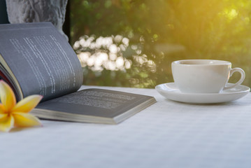 Books and coffee on the table to relax in the morning on a wooden table with light sunlight.