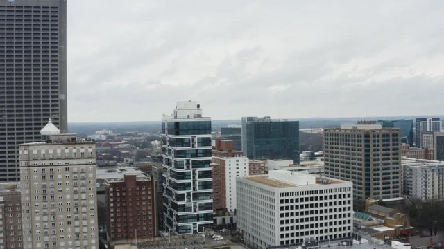 Drone shot above Midtown Atlanta on a cloudy day after a storm. Rising shot looking west over the Lilli and Georgian Terrace.