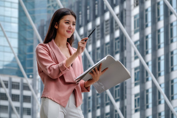 Fototapeta premium businesswoman is standing and working in front of office building in city