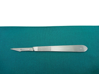 Surgical instrument, scalpel handle number 3 with blade number 11 on surgical green drape fabric isolated on white background  for copy space text.