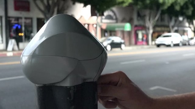 Closeup of a male hand inserting coins in a parking meter