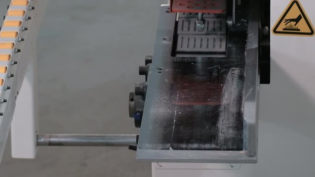 Furniture manufacturing workshop. The beginning of the movement of the chipboard sheet on the guide rollers. Machine for edging wooden parts. The real sound of a working machine.