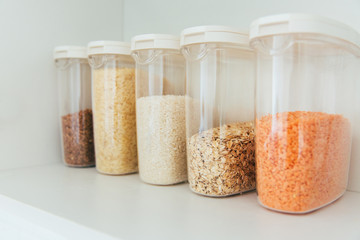 Various seeds in storage jars in pantry, white modern kitchen in background. Smart kitchen organization. Healthy cooking, clean eating concept.