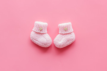 Pink knitted footwear for kids on pink background top view space for text