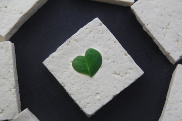 Heart shaped moringa or malunggay leaf on an uncooked tofu or soy bean curd