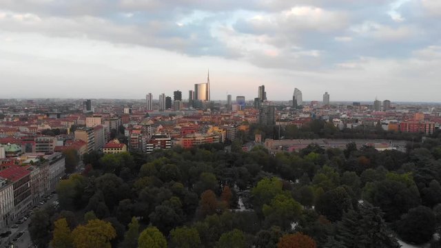 In Milan Italy, The drone flies left while panning right over the Sempione Park while looking at the city.