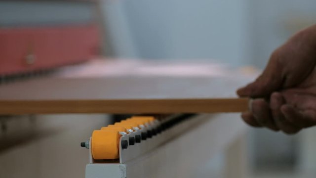 Machine for gluing edges on chipboard parts. Selective focus. Blurry. Particleboard movement on guide rollers. Shallow depth of field. Furniture manufacture. The real sound of a woodworking machine.