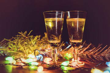 Glasses against the background of a garland. Drinking champagne in a romantic setting. The celebration of Christmas and new year together.