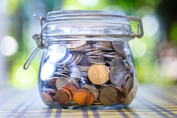 Many coins in glass jar, saving.