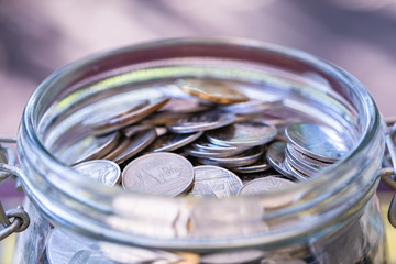 Many coins in glass jar, saving.