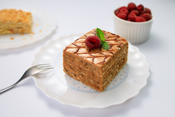 Cake piece with nuts, chocolate, biscuits and caramel cream on white table in a restaurant