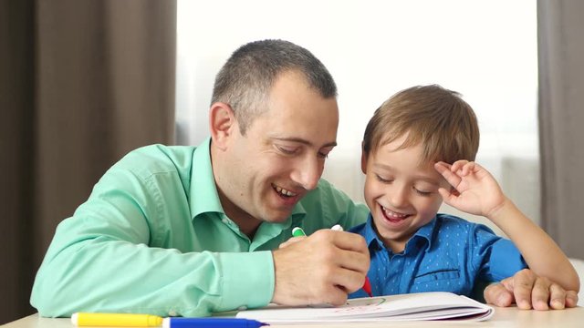 Happy family: father and son spend time painting with colored markers.