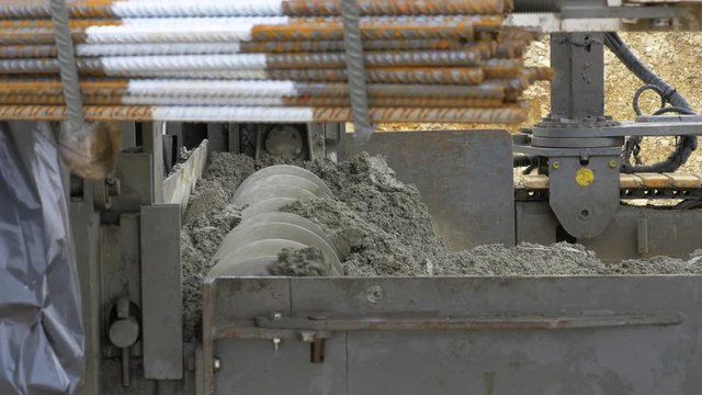 Fully mechanised process of concrete pavement construction. The slipform paver spreads the concrete over the full paving width with its auger. Preparation for laying a base layer.