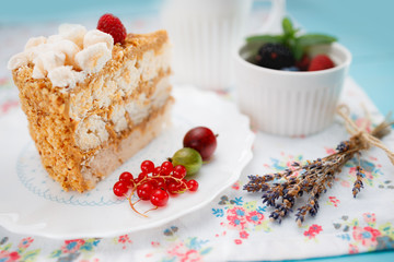 Cake piece with macaroons, chocolate, milk cream, nuts and fresh fruits on vintage wooden background