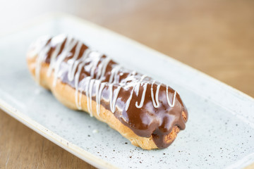 Traditional french eclairs with chocolate. Cake decorated with chocolate cream on top of are on a wooden table