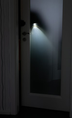 A burglar with a flashlight opens a door