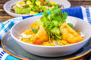 A bowl of vegetarian Dhal with flatbread and garnished with coriander