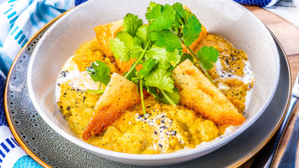 A bowl of vegetarian Dhal with flatbread and garnished with coriander