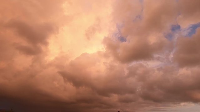 Timelapse of a dramatic cloudy sky with clouds quickly covering the sun on the blue sky at sunset on the silhouette of the hill tops