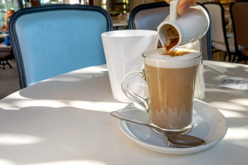 pouring cup of hot latte coffee into milk foam, Italian style