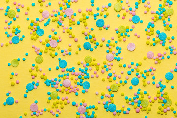 trendy pattern of colorful round sprinkles over yellow background, decoration for festive Valentines day, birthday, holiday and party time