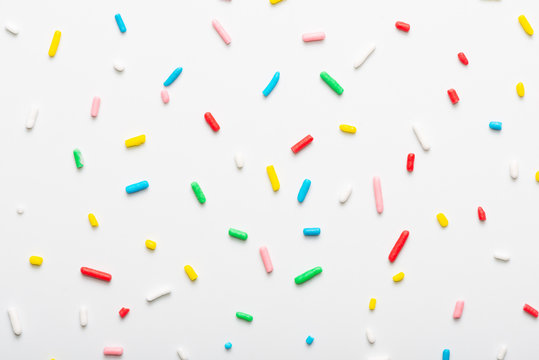 flat lay of colorful sprinkles over white background, festive decoration