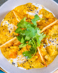 A bowl of vegetarian Dhal with flatbread and garnished with coriander