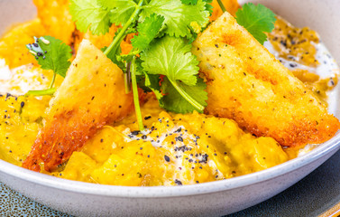 A bowl of vegetarian Dhal with flatbread and garnished with coriander