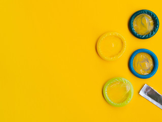 Flat lay colourful condoms on yellow background