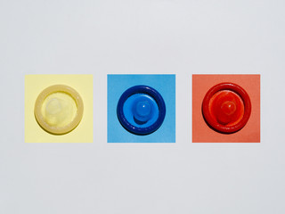 Flat lay coloured condoms on white background