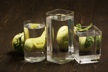 Foods distorted through liquid and glass on dark wooden background.