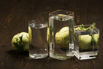 Foods distorted through liquid and glass on dark wooden background.