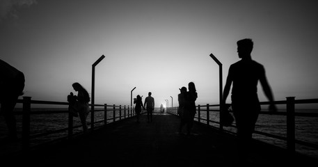Fototapeta na wymiar Walking people silhouettes on bridge