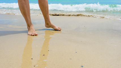 Closeup of woman's feet walking on the beach during a golden sunset.
