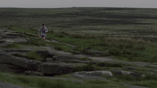 Young fitness man running British trail ridge, beautiful scenery run 