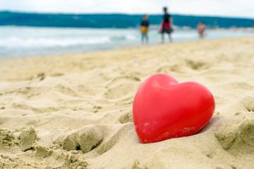 Fototapeta na wymiar Heart on the sand on the summer beach with sea background. Close-up.