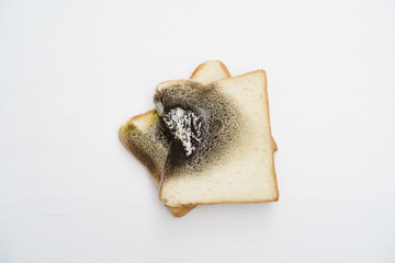 Moldy bread on wooden white background.