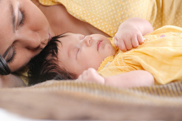 Pretty young woman holding a newborn baby in her arms. Happy family concept.