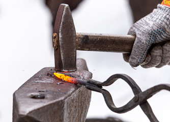 A blacksmith bends metal with a hammer