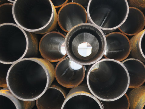 looking through a pile of rusty round metal pipes
