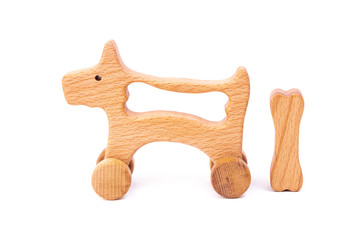 Photo of a wooden dog with bone on wheels  of beech. Toy made of wood  on a white isolated background.A toy for entertaining children and resting parents