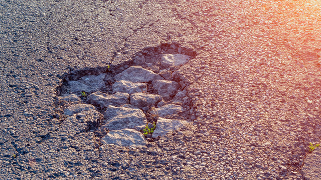 pothole on asphalt closeup with blue and gray stones. Background texture