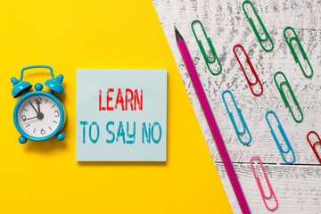 Handwriting text Learn To Say No. Conceptual photo decline or refuse few things before you destroy yourself Notepad marker pen colored paper sheet clips alarm clock wooden background