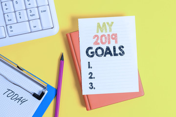 Writing note showing My 2019 Goals. Business concept for setting up demonstratingal goals or plans for the current year Pile of empty papers with copy space on the table