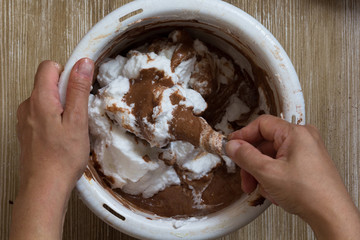 Hand of woman stirring batter with whisked whites in bowl before baking