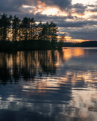 Midnight sun with water reflection at lake in Finland.