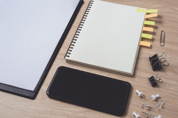 Workspace with diary or notebook and smart phone, clipboard, pencil, sticky notes on wooden background