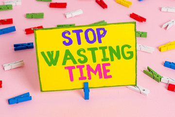 Word writing text Stop Wasting Time. Business photo showcasing advising demonstrating or group start planning and use it wisely Colored clothespin papers empty reminder pink floor background office